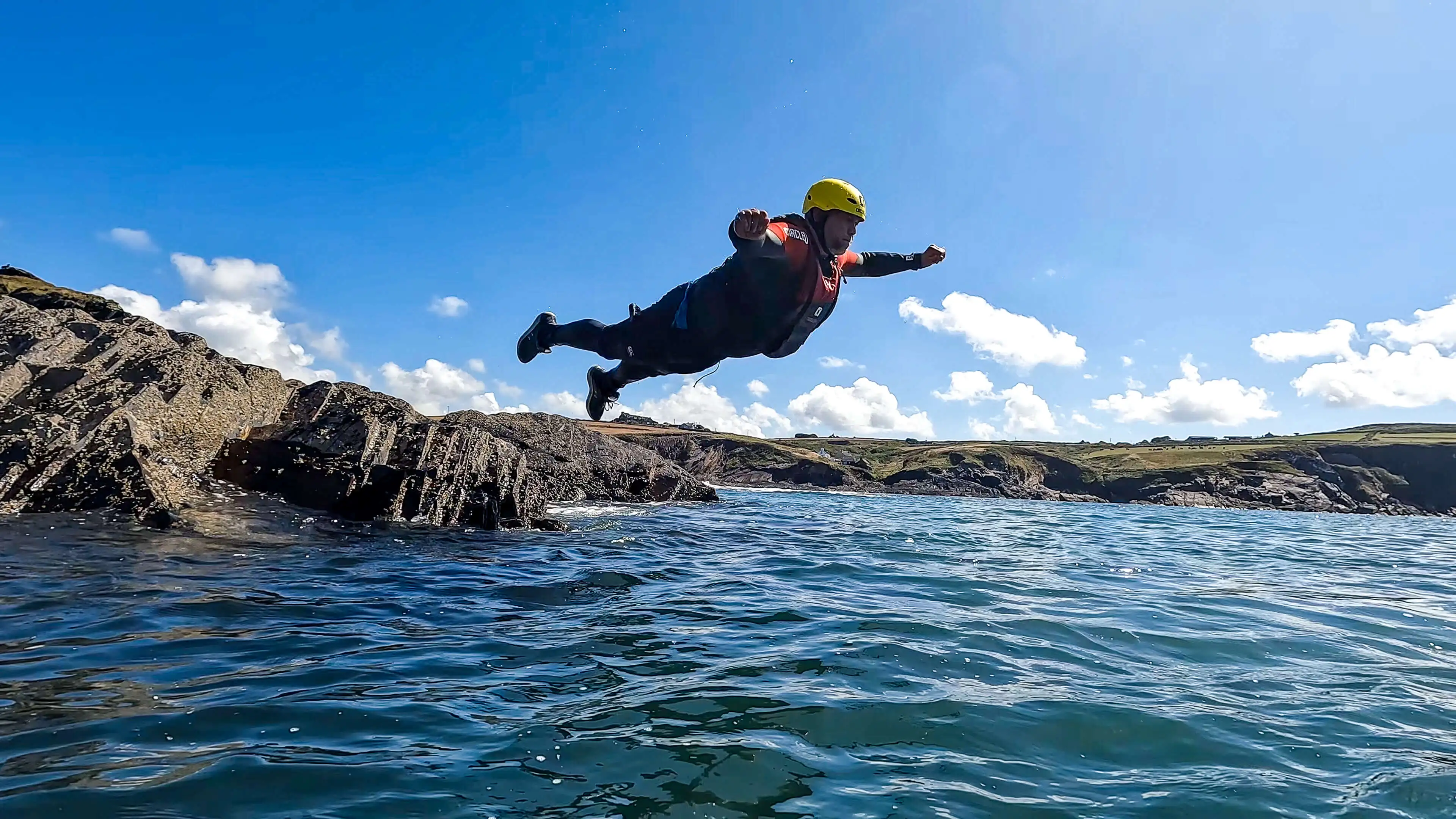 A guy is belly flopping off the coastline in Pembrokeshire.